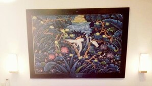 A hotel room with a bed, pillows, a blanket, and a painting on the wall. - Padanta Homestay (Gili Trawangan)