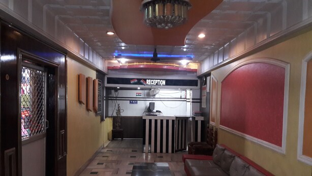 A reception area with a reception desk, a sofa, and a small table. - Hotel Sheela International (Durg)
