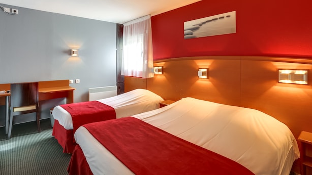 Habitación de hotel con dos camas, un escritorio y una silla.
