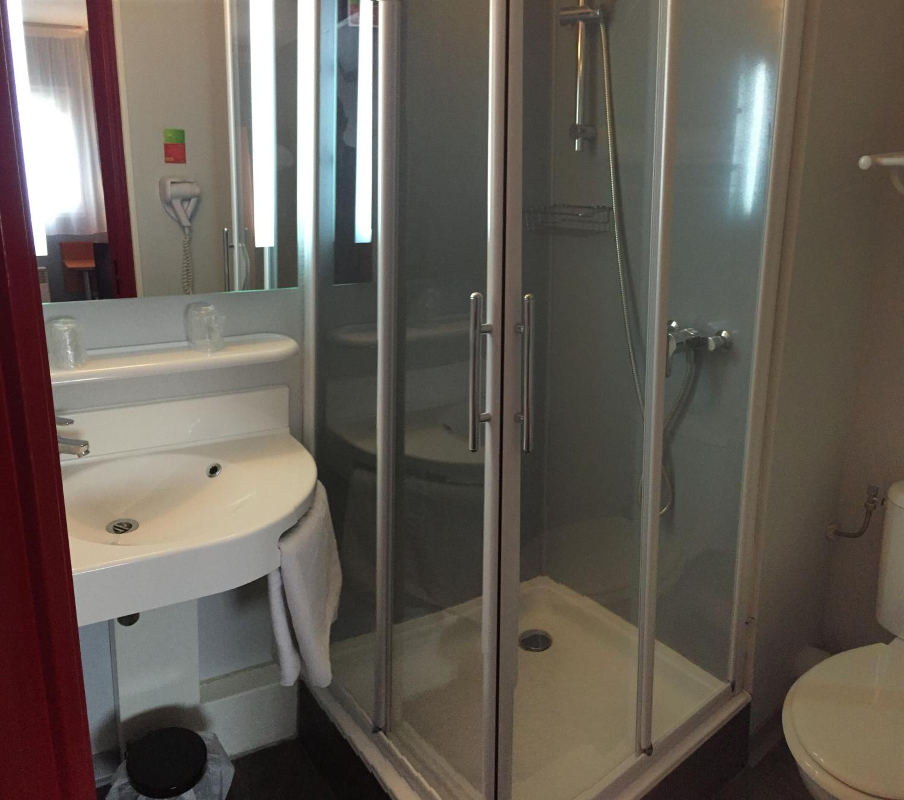 A bathroom with a glass-enclosed shower, a white sink, and a toilet.