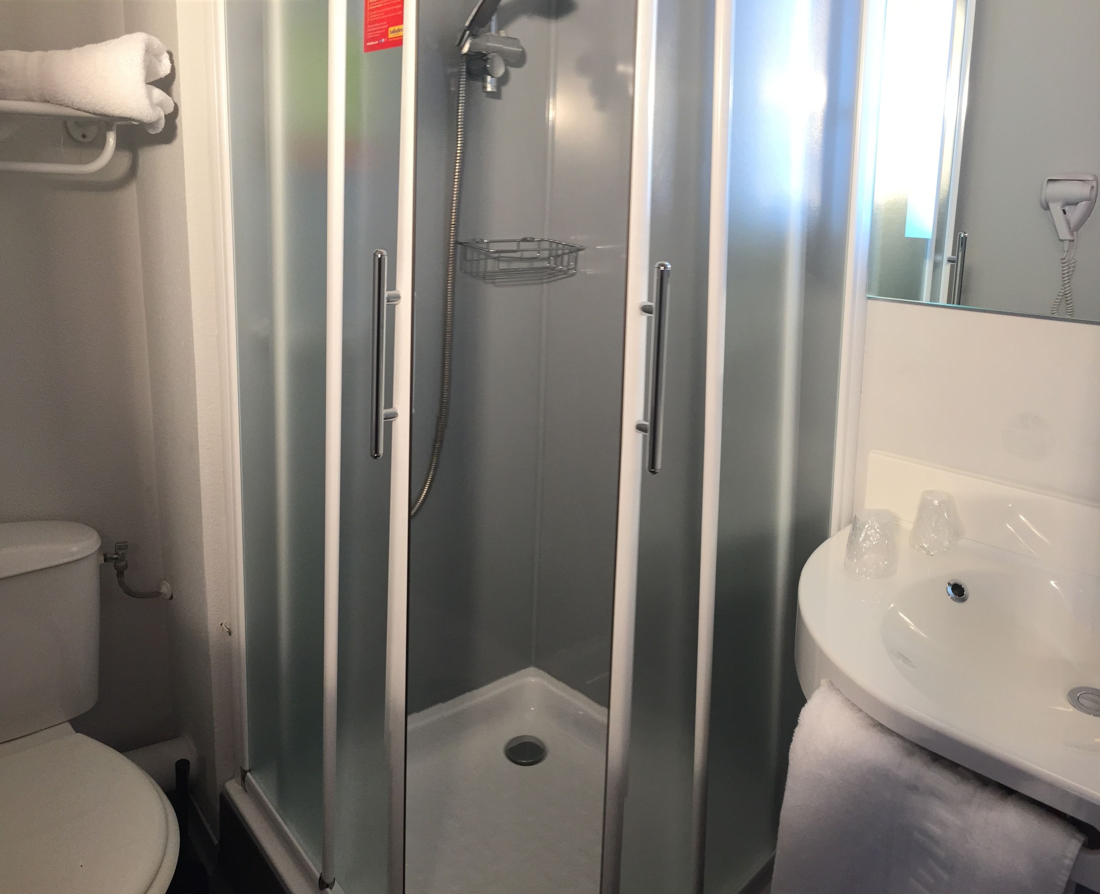A bathroom with a glass-enclosed shower, a white sink, and a toilet.