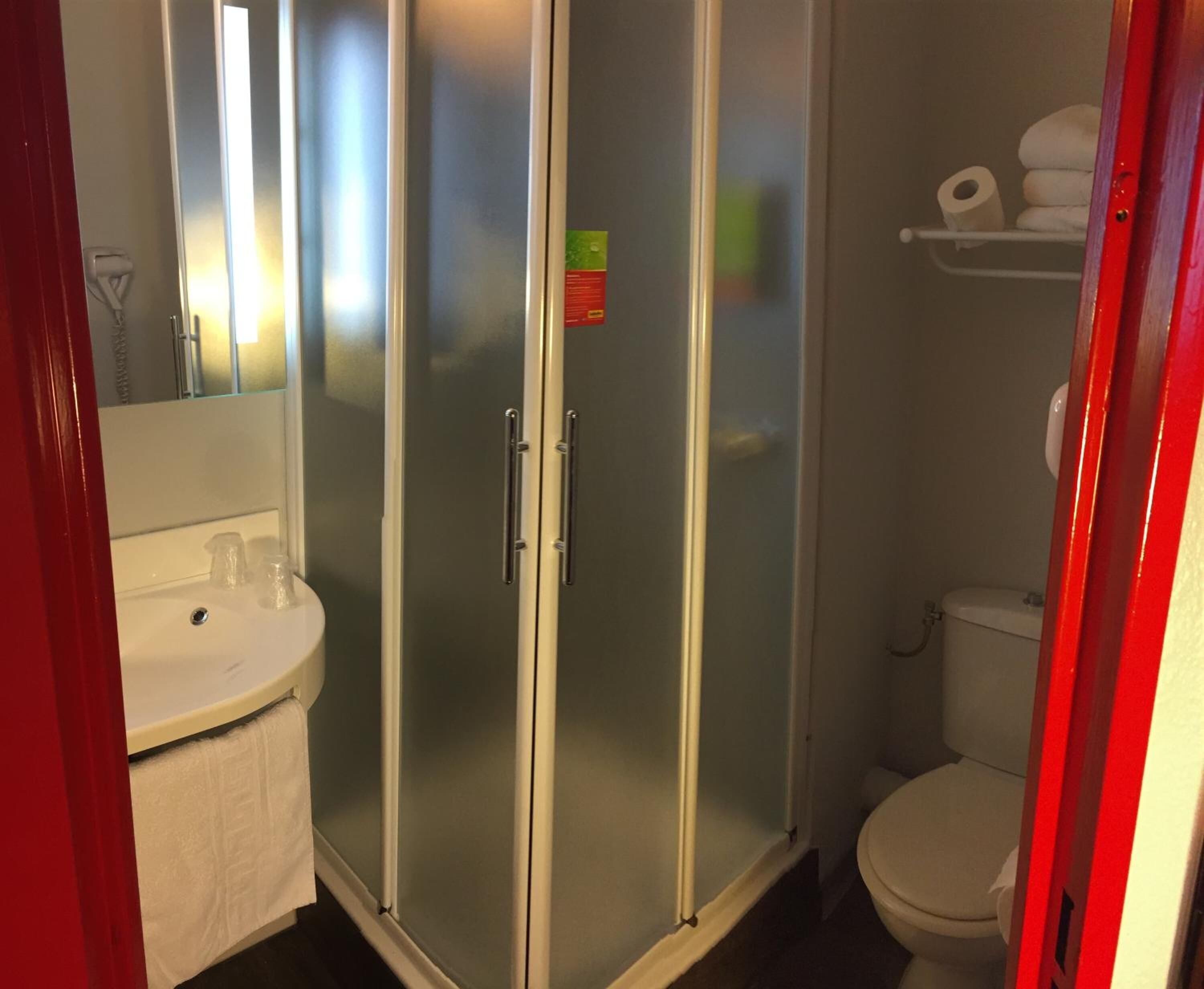 Un bagno con doccia vetrata, un lavandino bianco e un water.