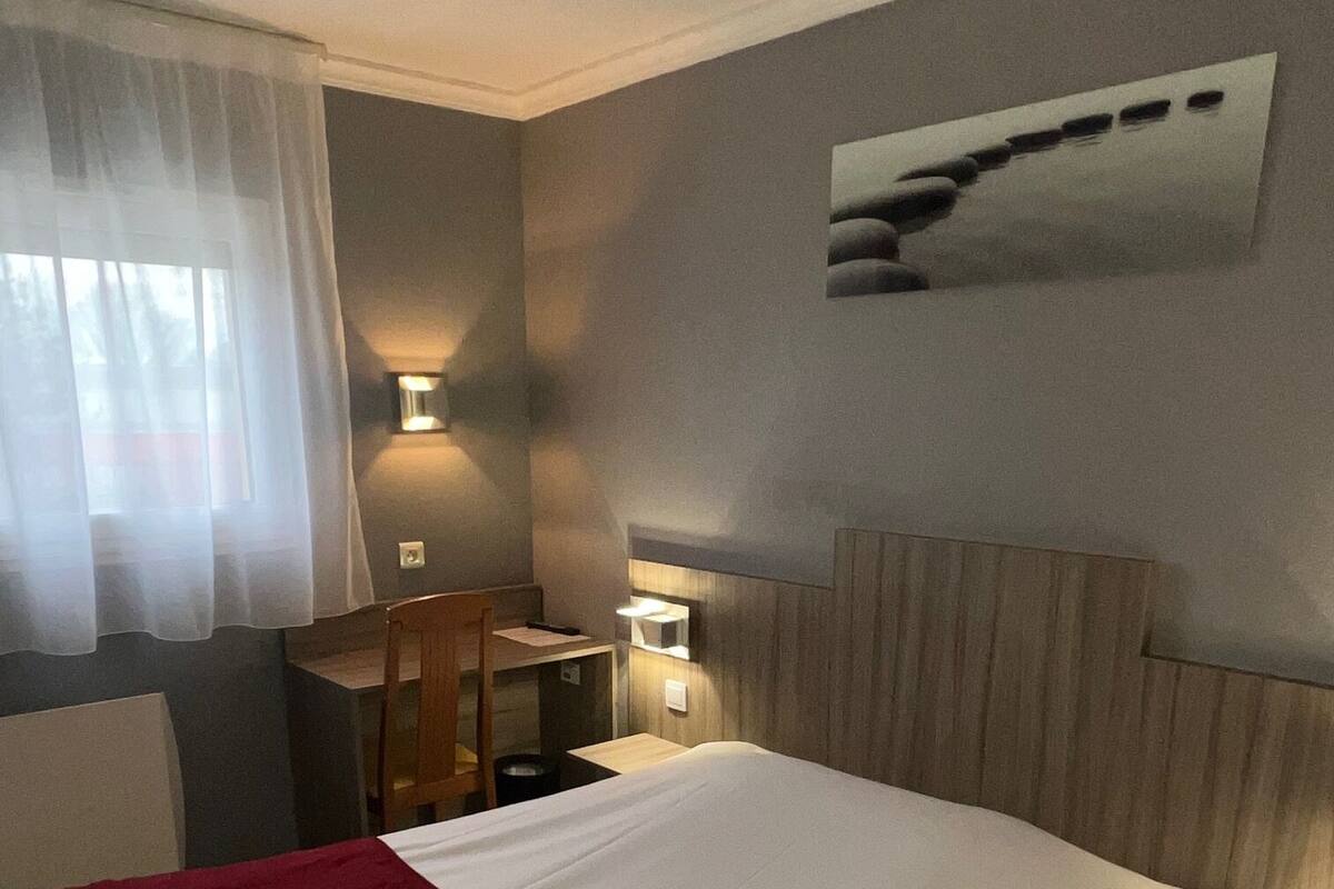 Una habitación de hotel con una cama grande, un escritorio y dos lámparas de pared.
