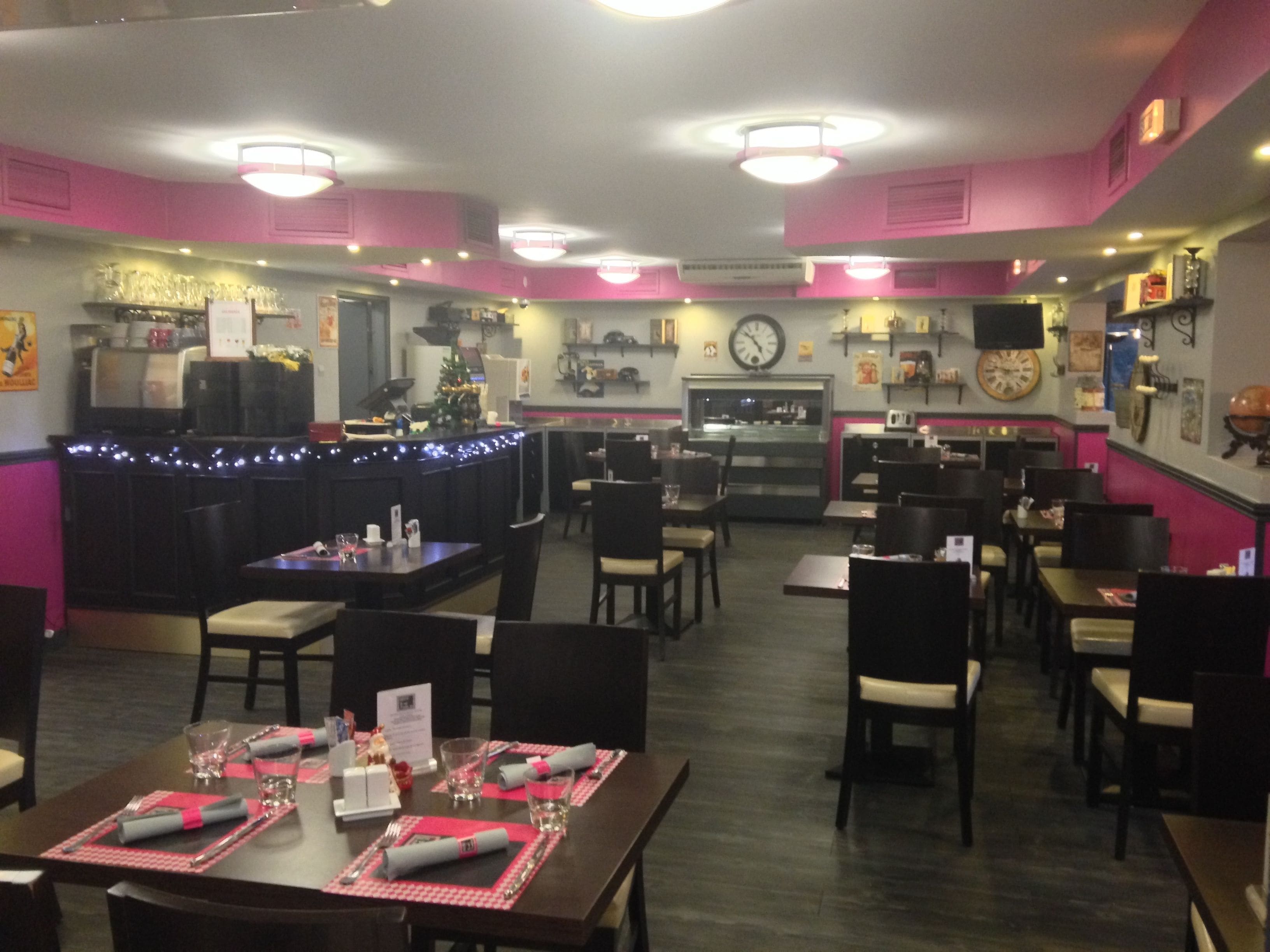 A restaurant with a bar area, tables set for dining, and a kitchen in the background.