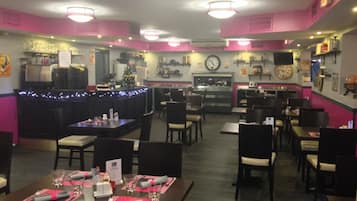A restaurant with a bar area, tables set for dining, and a kitchen in the background.