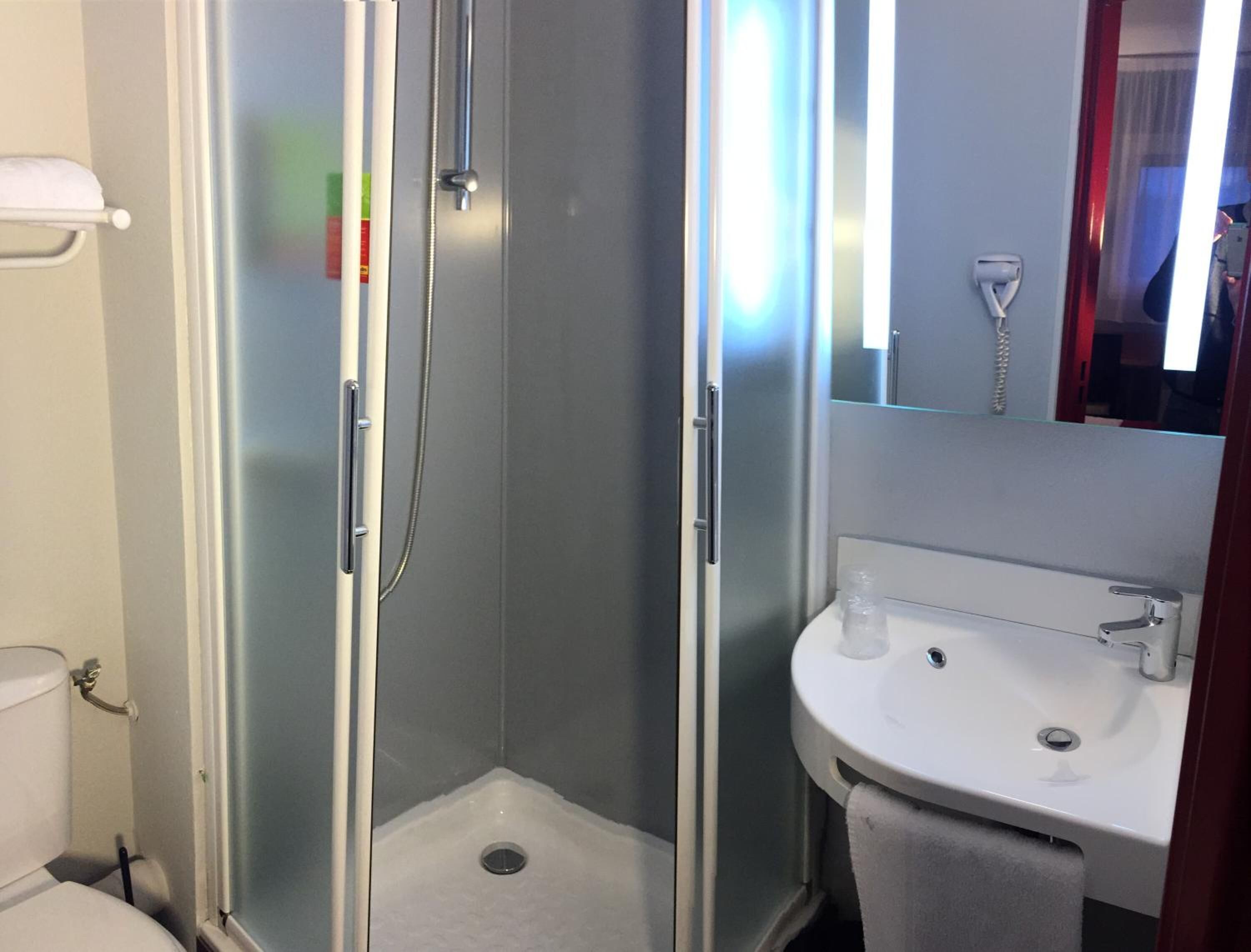 A bathroom with a glass-enclosed shower, a white sink, and a mirror above the sink.
