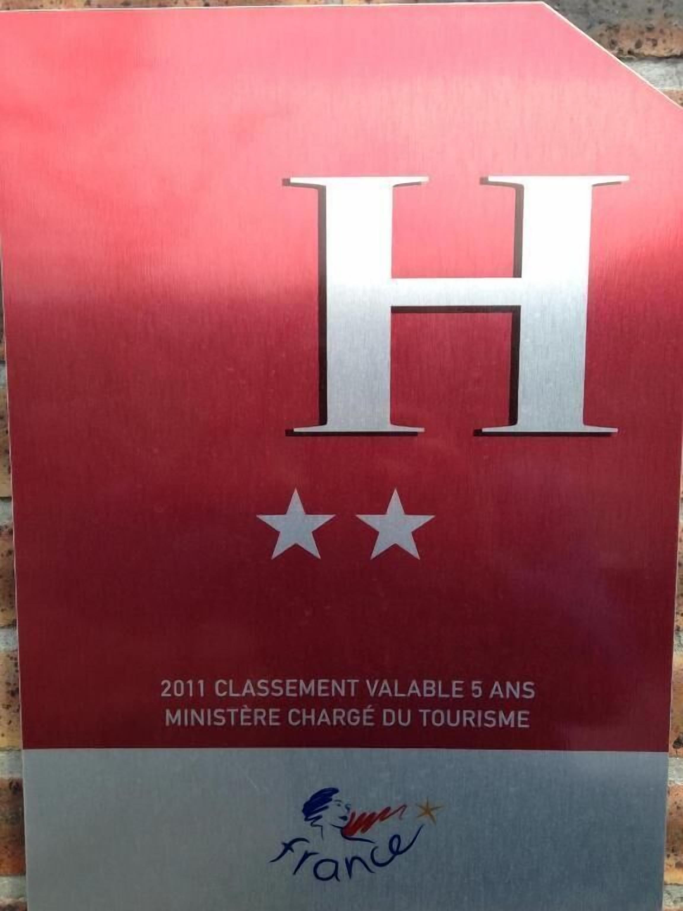 Un letrero rojo y gris con una 'H' blanca grande y dos estrellas debajo. El texto dice '2011 CLASSEMENT VALABLE 5 ANS MINISTÈRE CHARGÉ DU TOURISME' y un logotipo con una 'Francia' estilizada y una estrella.