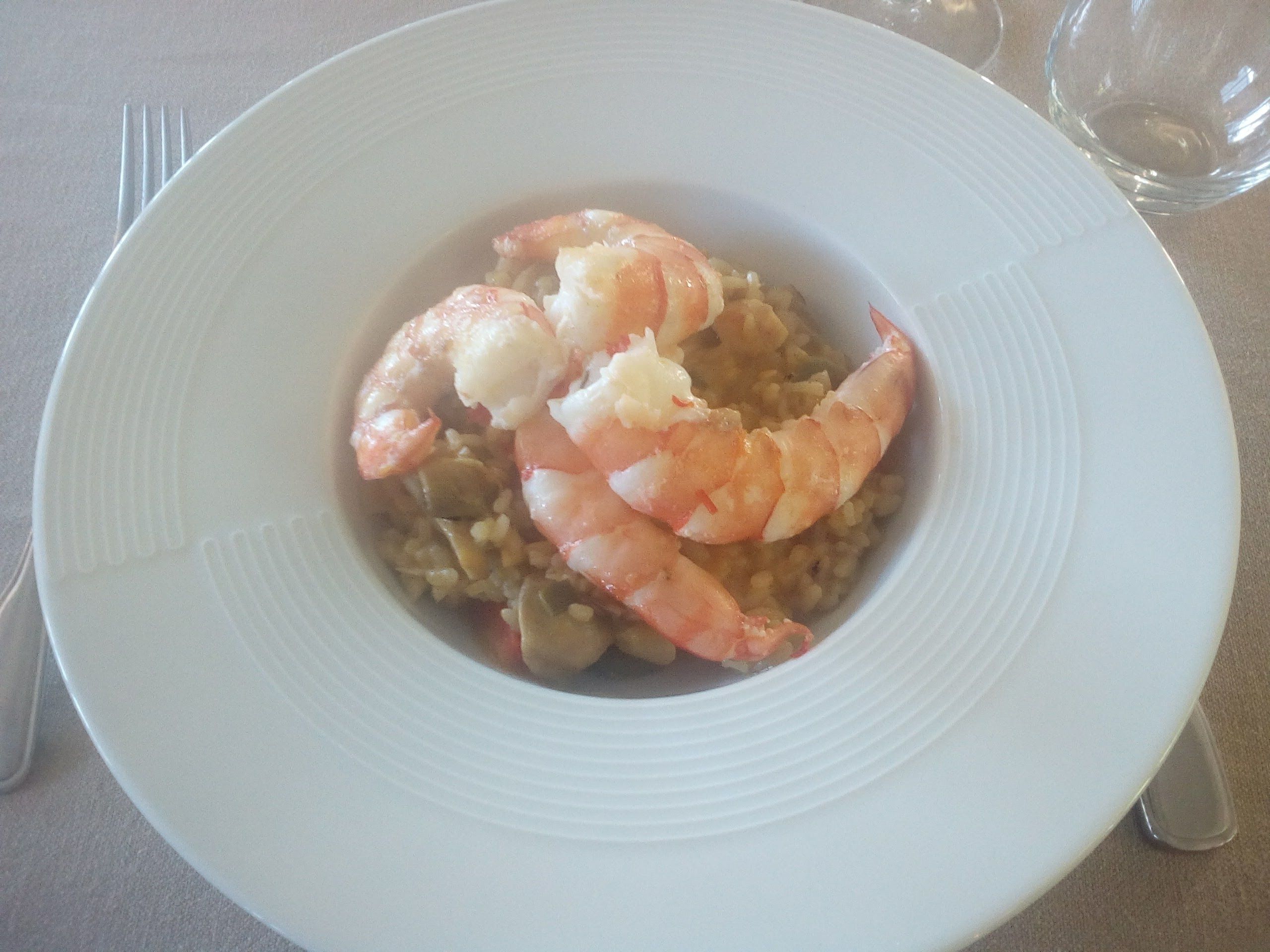 A plate of seafood risotto with shrimp on a white plate.