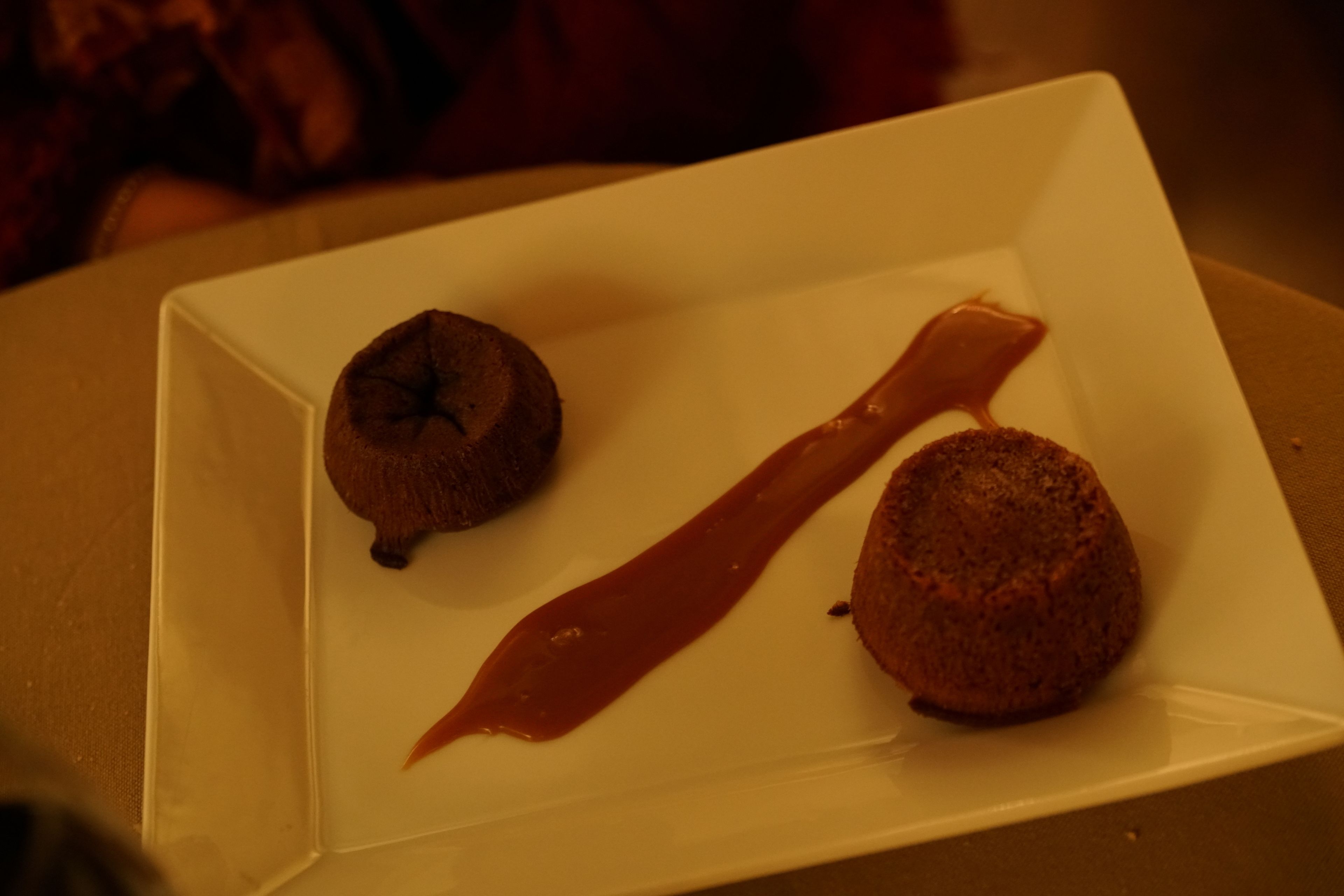 Ein weißer Teller mit zwei runden Desserts und Schokoladensauce.