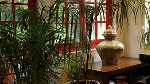 Una planta en maceta, un jarrón decorativo y un escritorio de madera con libros y papeles.