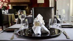 Una mesa de comedor preparada con un mantel doblado, un plato y dos copas de vino.