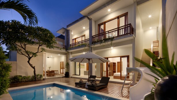 A two-story building with a swimming pool, outdoor seating, and a balcony with plants. - Daha Mansions Seminyak (Seminyak)