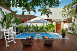 A wooden deck with a pool, lounge chairs, and a ladder.