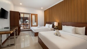 A hotel room with two beds, a wooden headboard, a flat-screen TV, a glass table, and a sliding door leading to a balcony. - Daha Mansions Seminyak (Seminyak)