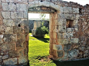An ancient stone archway leading to a grassy area with a stone wall in the background. - Masseria Costarella (Melendugno)