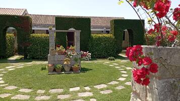 Une cour avec un chemin en pierre, des plantes en pot et une pergola.