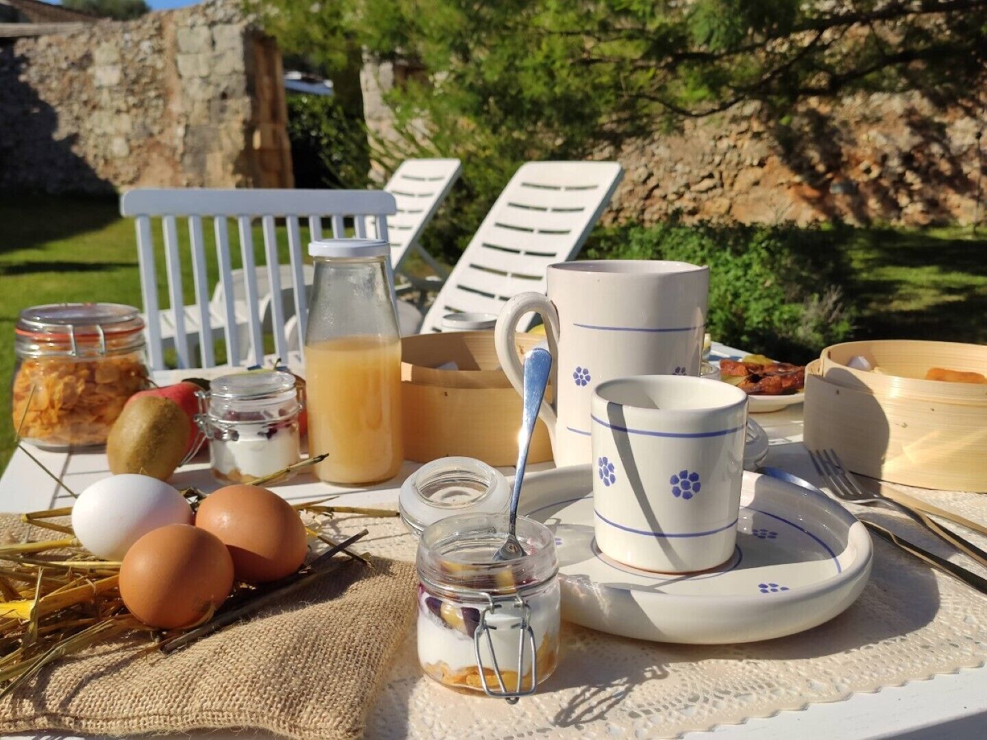 A breakfast setup with eggs, a bottle of juice, and a mug on a table outdoors.