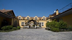 A courtyard with a central staircase leading to a building with multiple balconies. - Agriturismo Il casale delle Ginestre (Fiumicino)