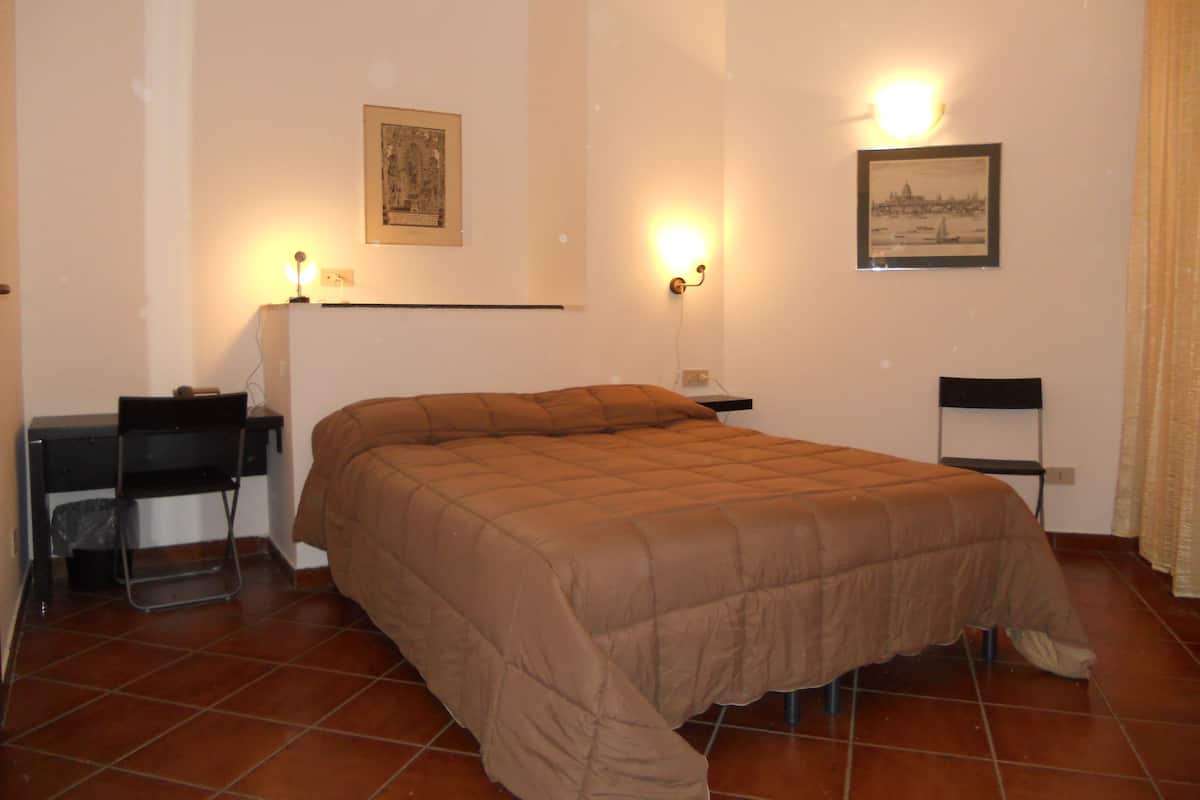Ein Schlafzimmer mit einem Bett, einem Schreibtisch, einem Stuhl und zwei Wandleuchten.