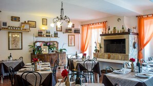 A dining area with multiple tables set for meals, a fireplace, and various wine bottles displayed on shelves. - Agriturismo Il casale delle Ginestre (Fiumicino)