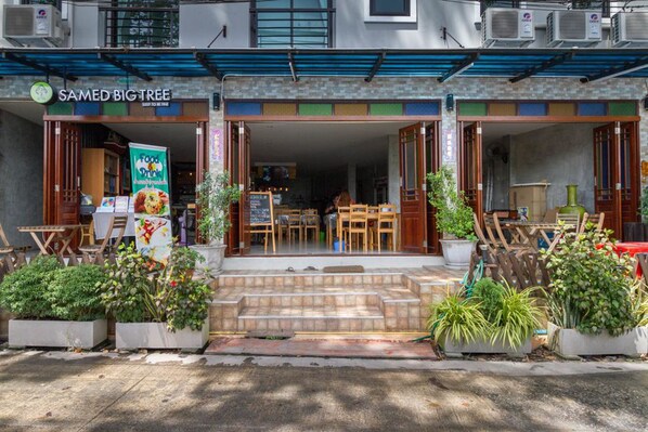 Un restaurante llamado "Samed Big Tree" con mesas al aire libre y plantas en macetas.