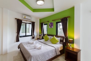 A hotel room with a large bed, green walls, and a window with curtains.