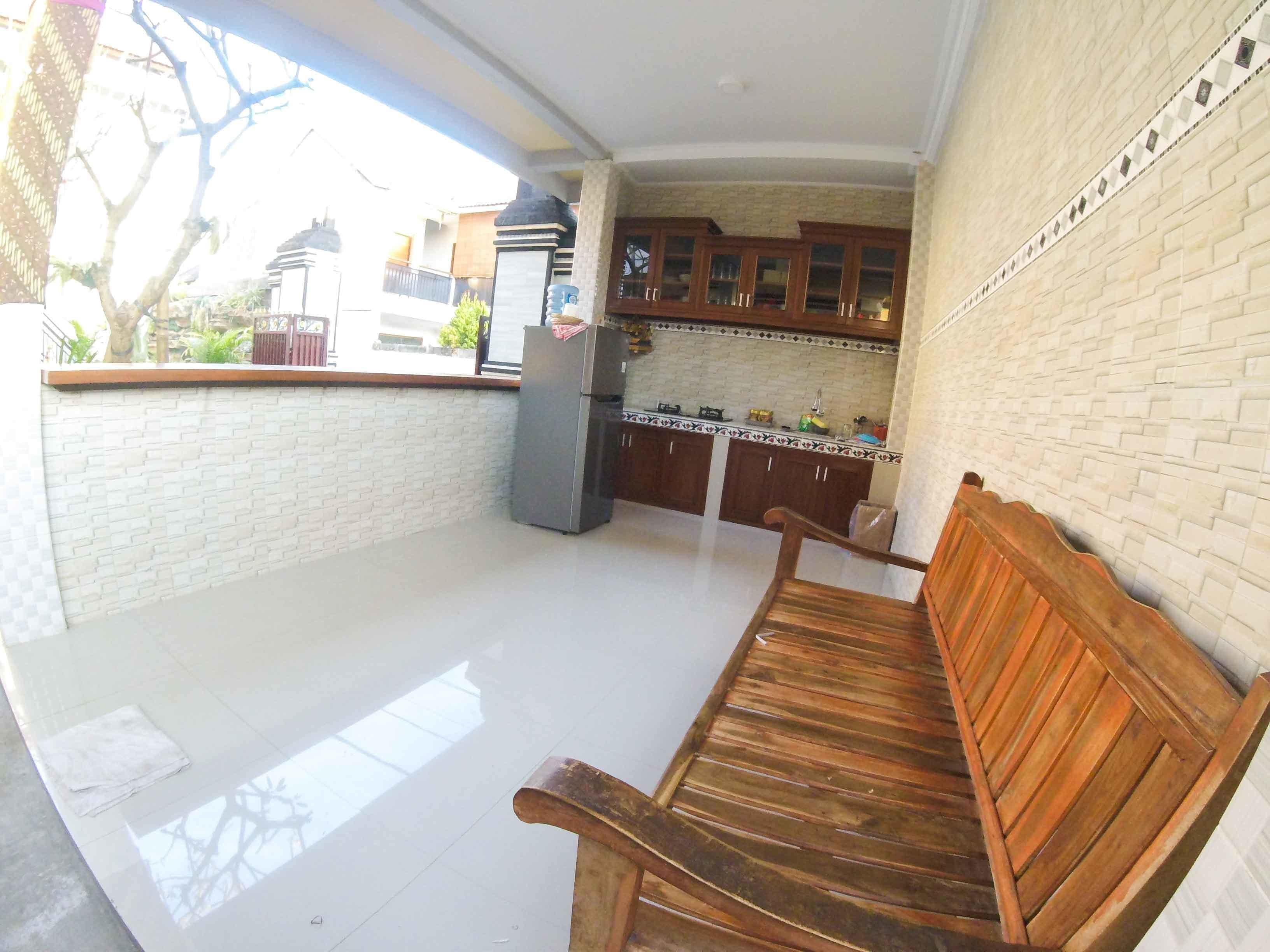 A kitchen with a wooden bench, white tiled floor, and a brick wall.