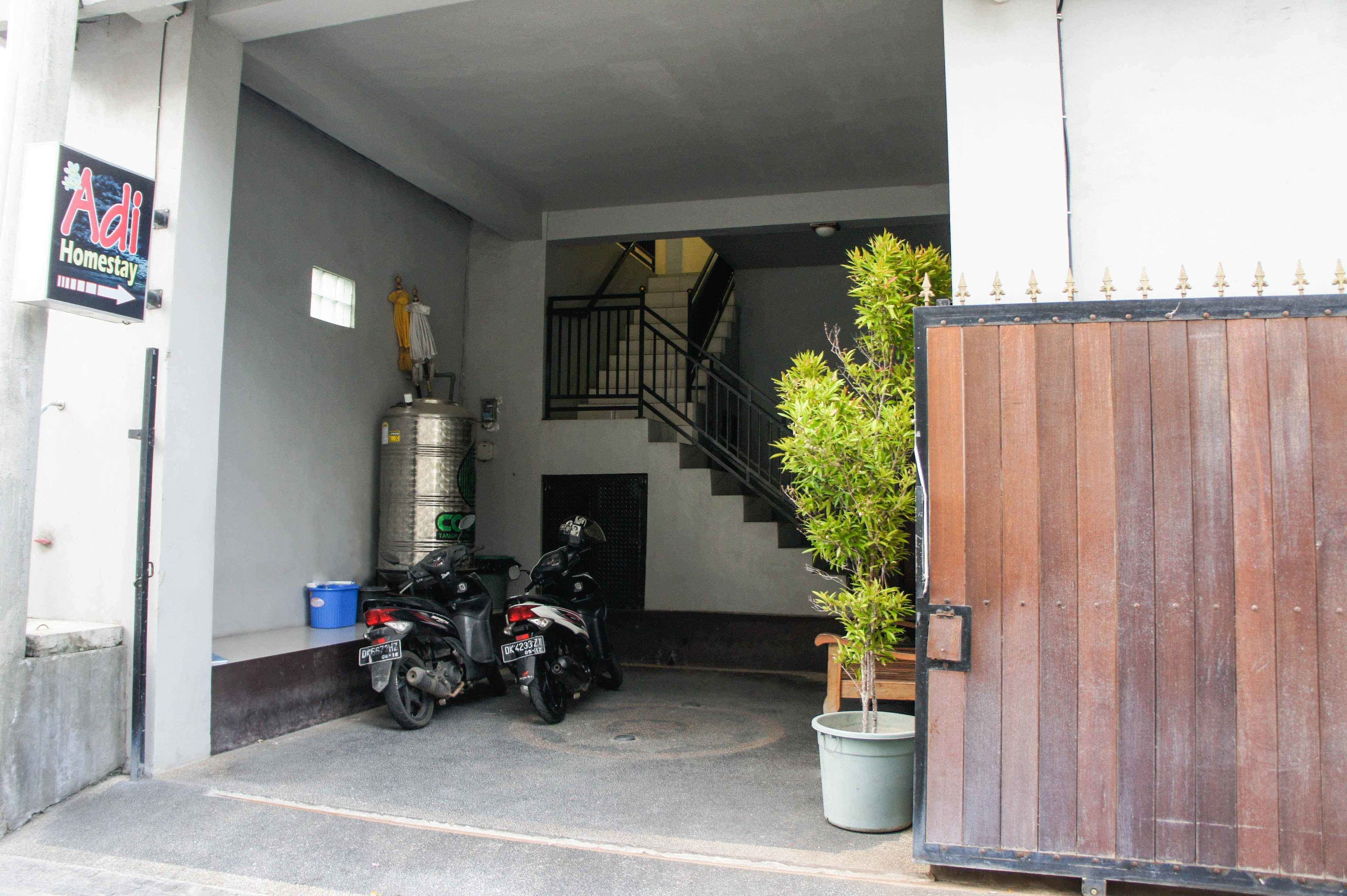 A building entrance with a staircase, a metal water tank, and parked motorcycles.