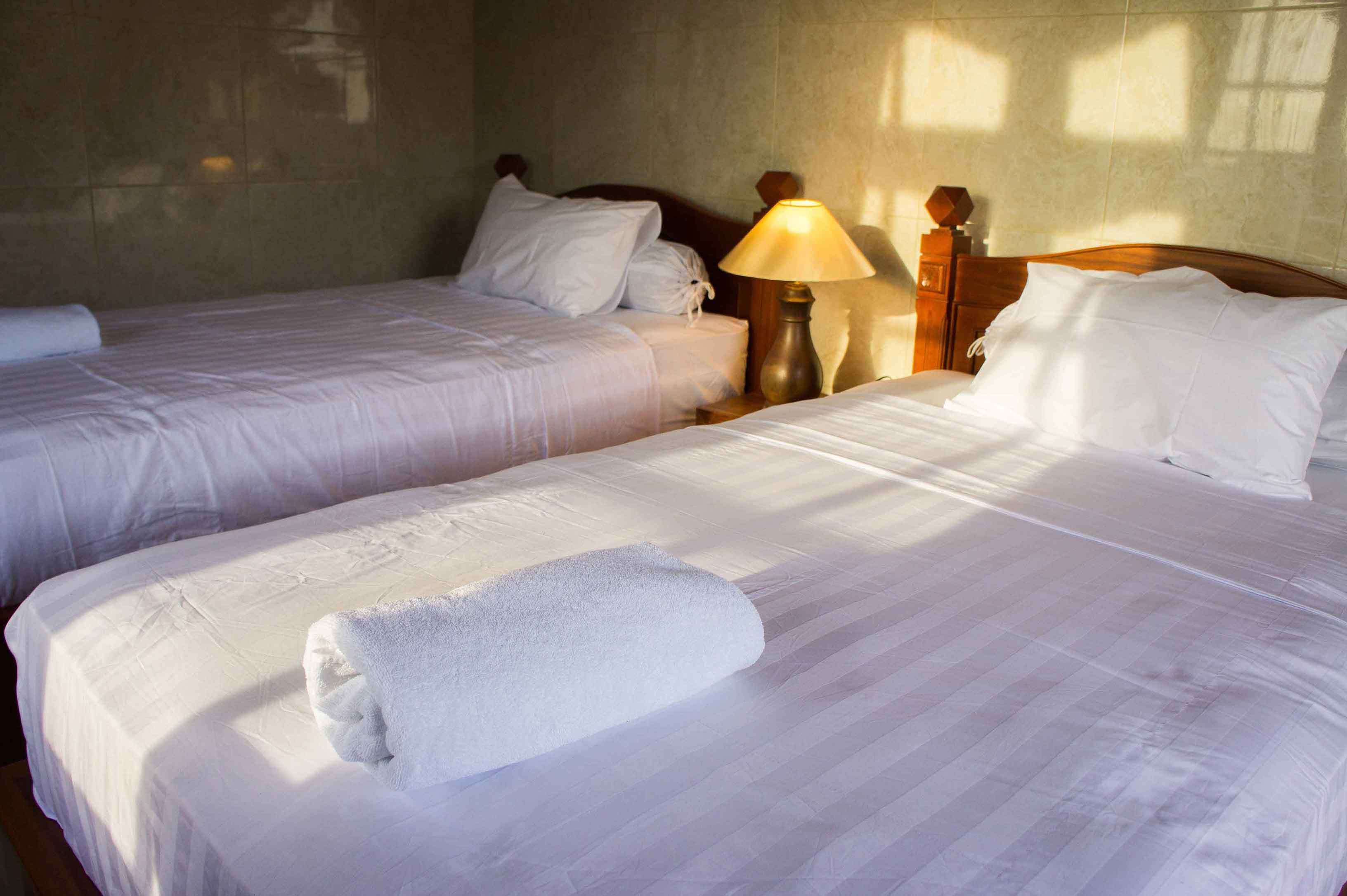 Ein Hotelzimmer mit zwei Einzelbetten, einem Nachttisch mit Lampe und einem Holzkopfteil.