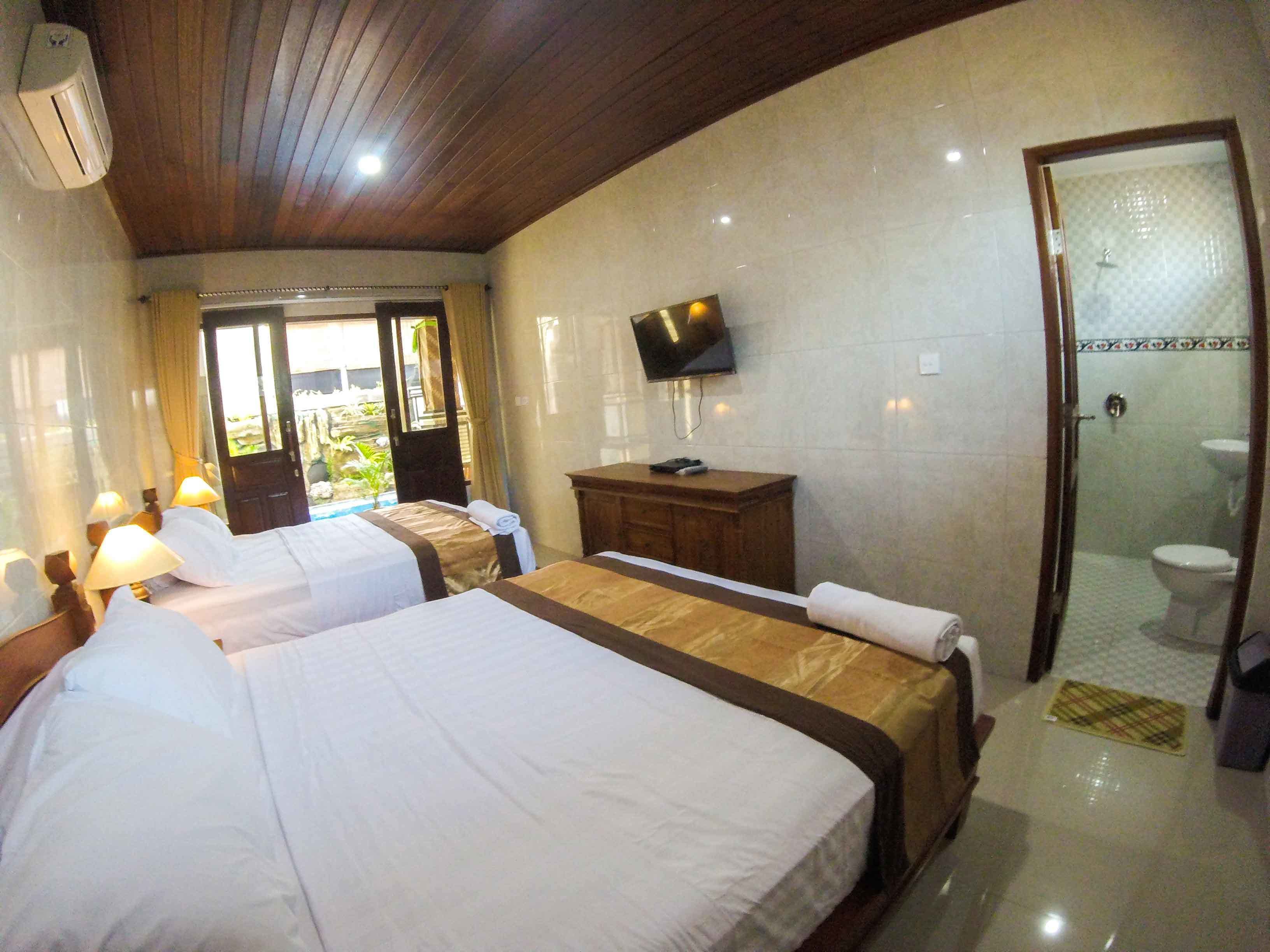 Une chambre d’hôtel avec deux lits, une télévision, une armoire en bois et une salle de bain avec douche et toilettes.