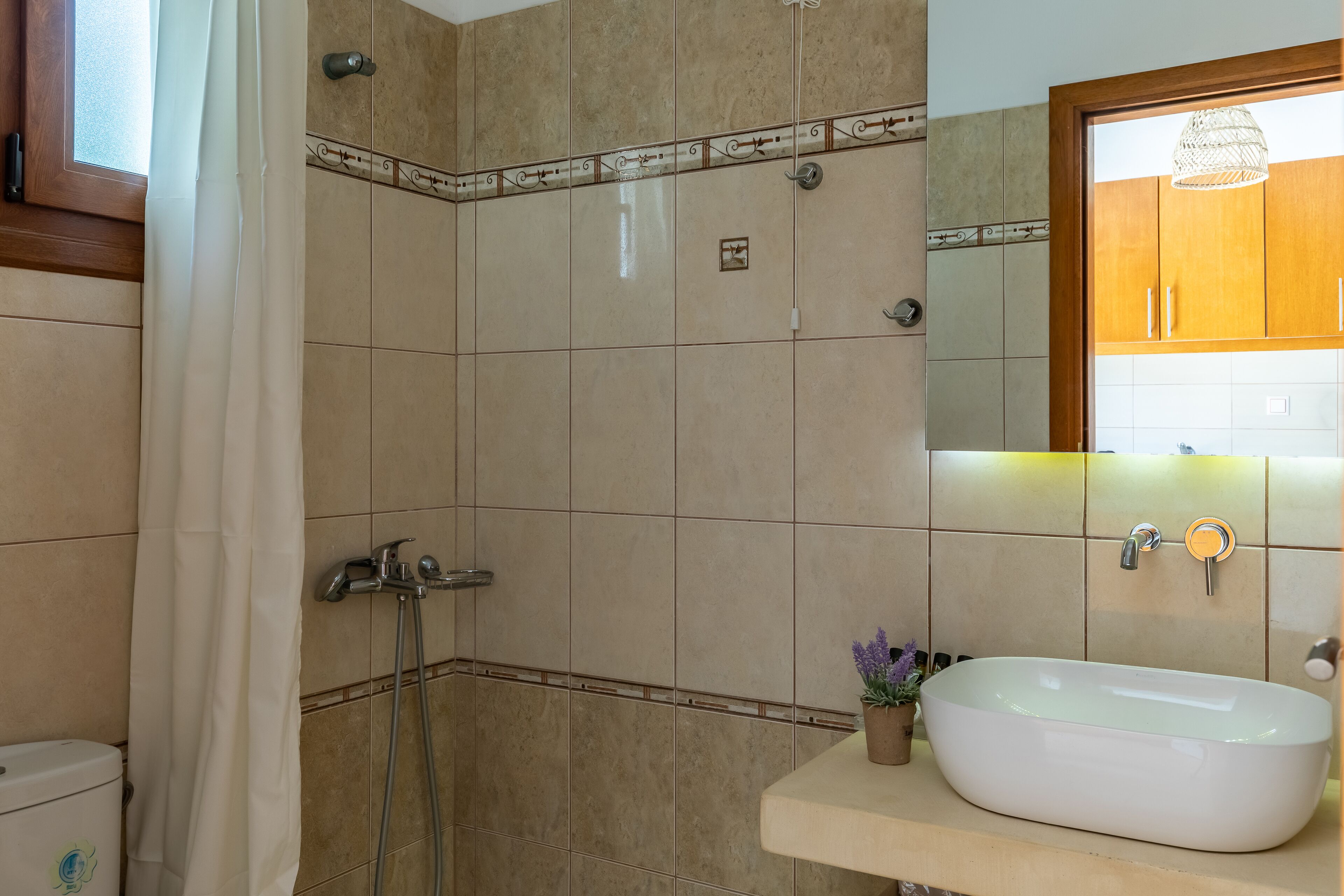 Un baño con ducha, inodoro, lavamanos y espejo.