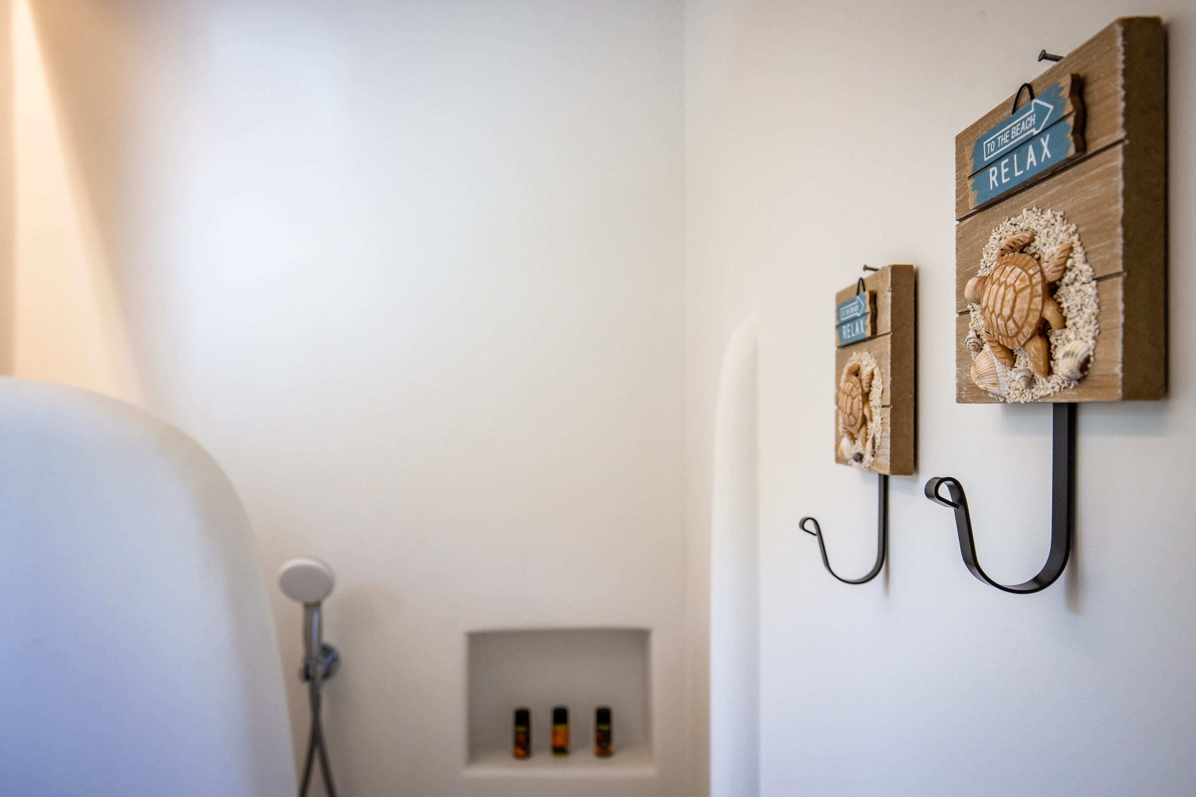 Een badkamer met een douche, een handdoekhouder en een klein plankje met toiletartikelen.