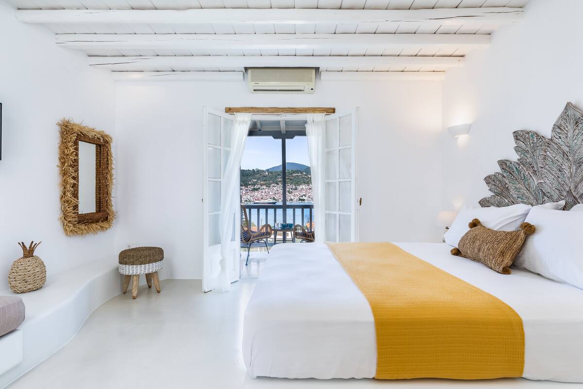 Une chambre à coucher avec un lit, un balcon offrant une vue, un miroir et un climatiseur fixé au mur.