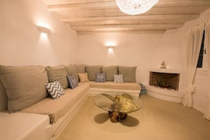 Una sala de estar acogedora con un sofá modular, una mesa de centro de vidrio y una chimenea.
