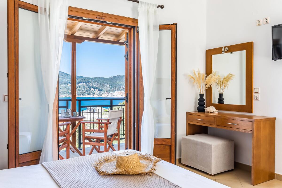 Une chambre à coucher avec un lit, un bureau, une chaise et une vue sur l’extérieur.