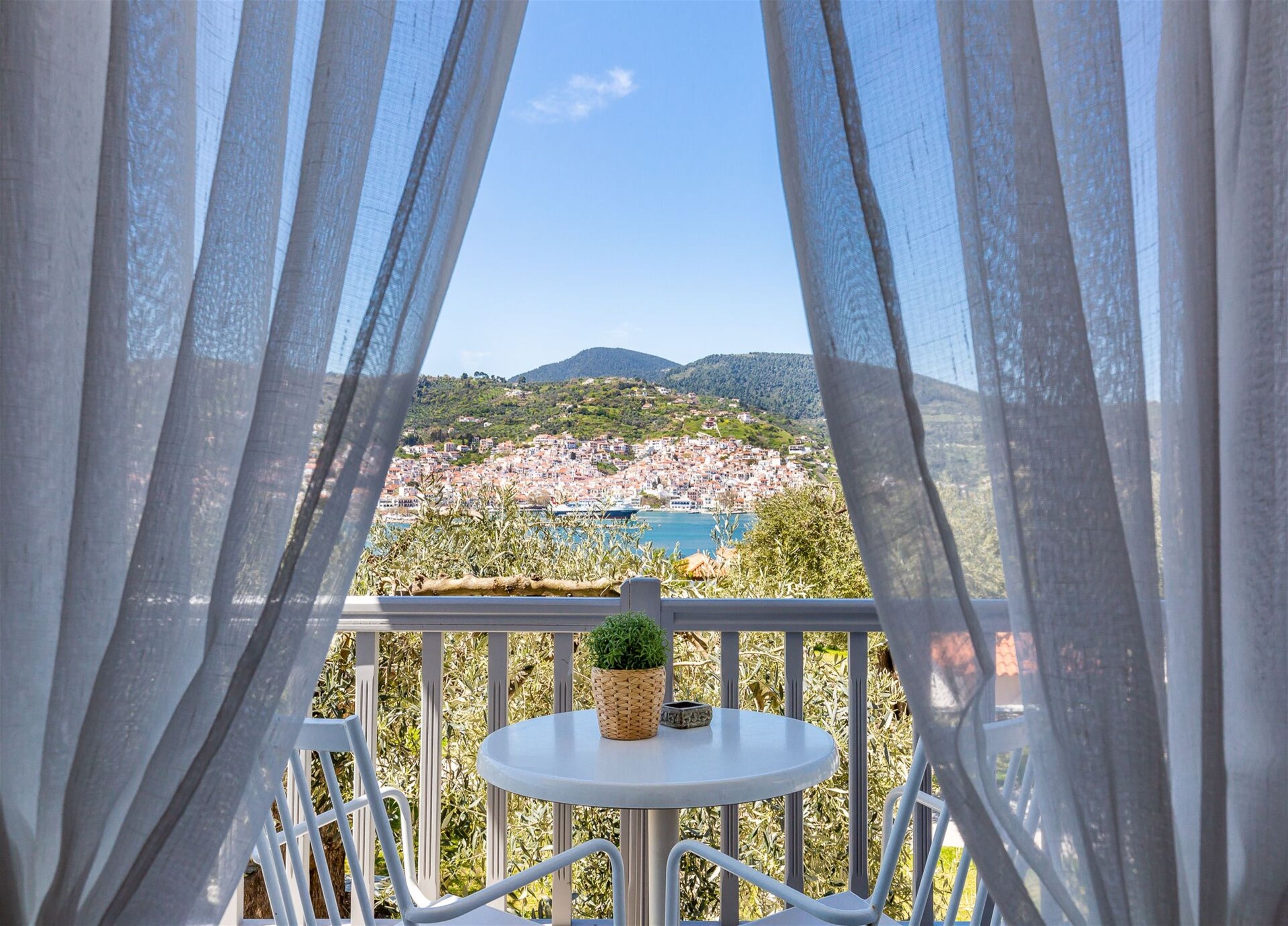 Un balcon avec vue sur une ville côtière et les montagnes.