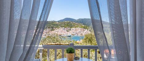 Un balcon avec vue sur une ville côtière et les montagnes.
