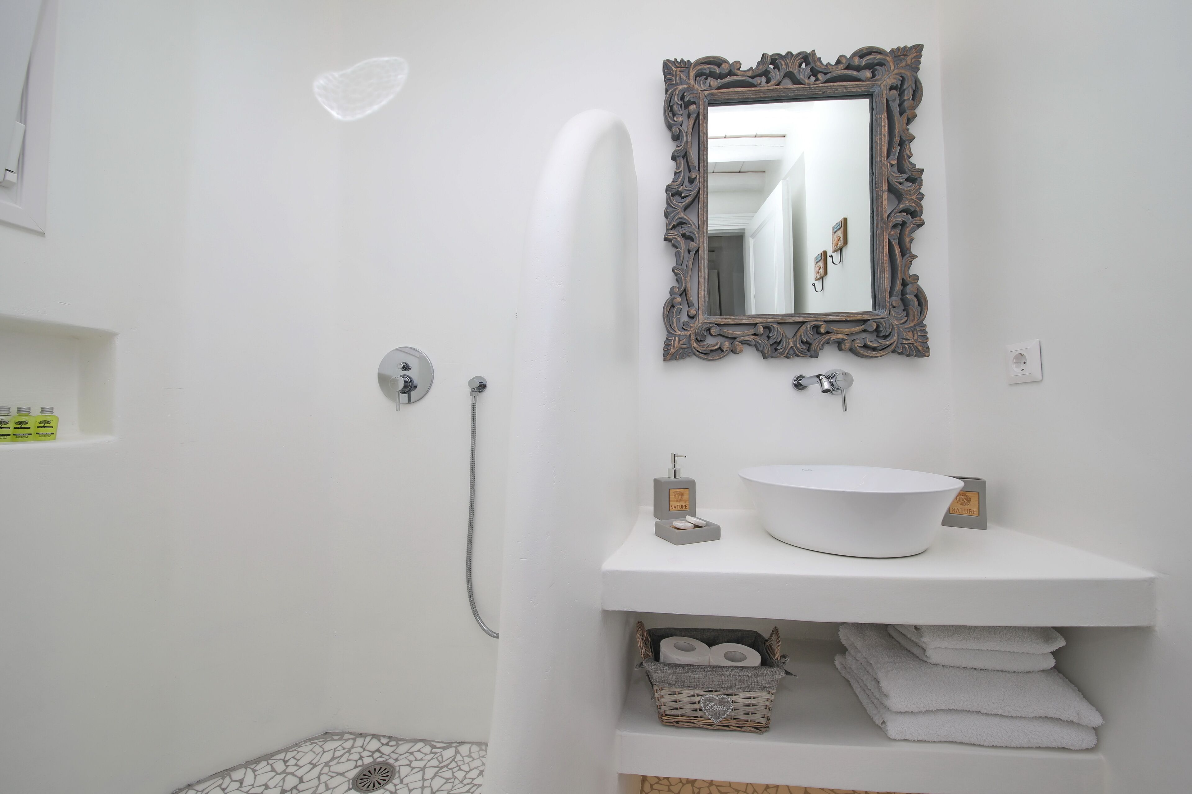Een badkamer met een wit wastafel, een spiegel met een versierde lijst, een douche en een handdoekrek.