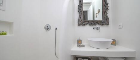 Een badkamer met een wit wastafel, een spiegel met een versierde lijst, een douche en een handdoekrek.