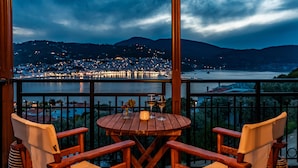 A wooden table with two chairs on a balcony overlooking a cityscape at night. - Evlalia Studios & Villas (Skopelos)