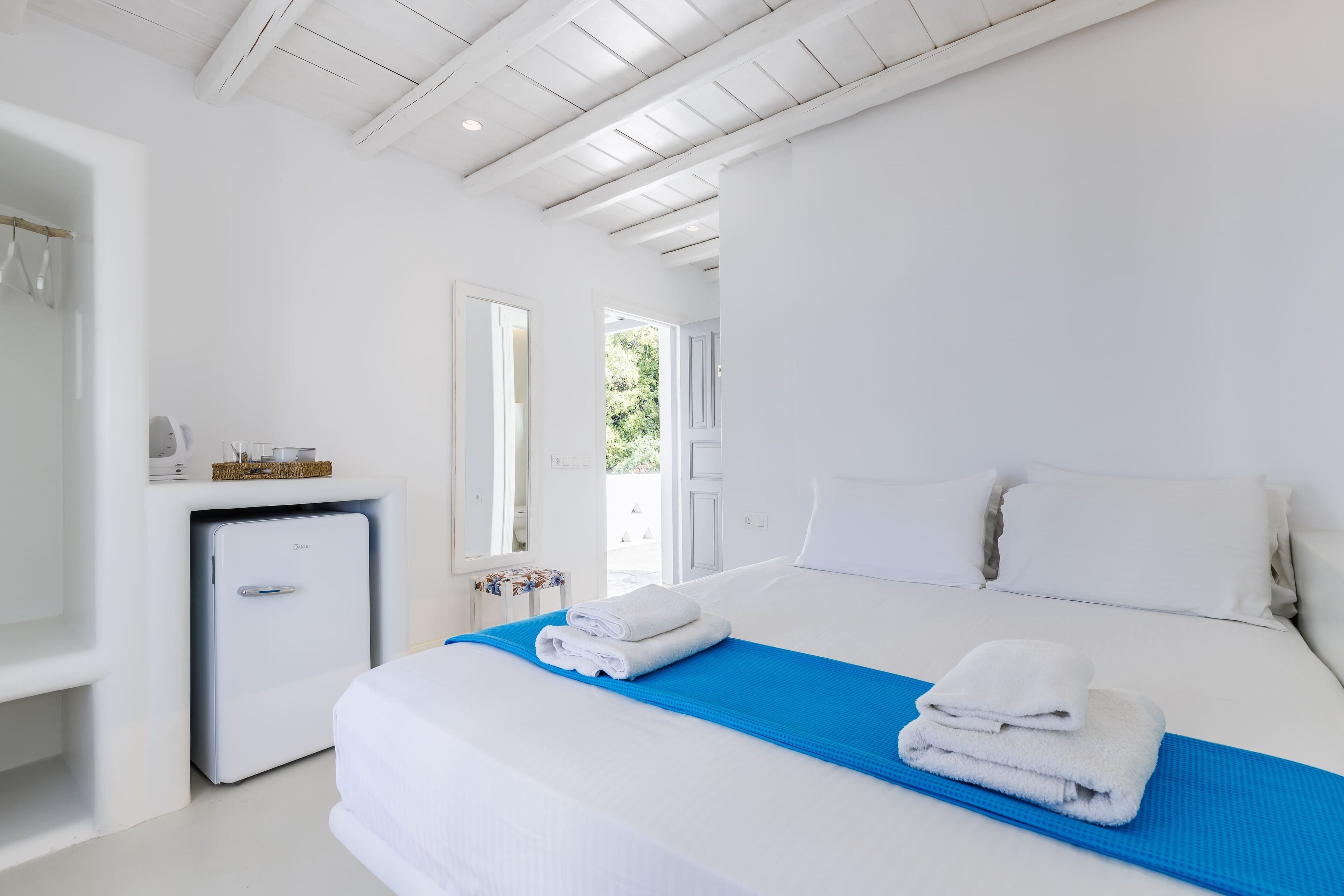 Habitación de hotel con cama, un refrigerador pequeño y vistas al exterior.