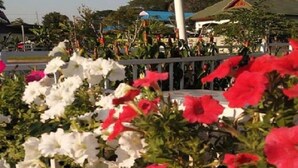 A garden with white and red flowers, a white fence, and a building in the background. - Sweet Mango Resort (Sung Noen)