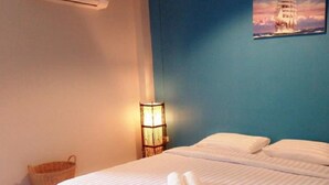 A hotel room with a bed, a wall lamp, and a painting of a ship. - Sweet Mango Resort (Sung Noen)
