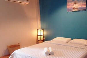 Quarto de hotel com uma cama, um abajur e um quadro de um navio.