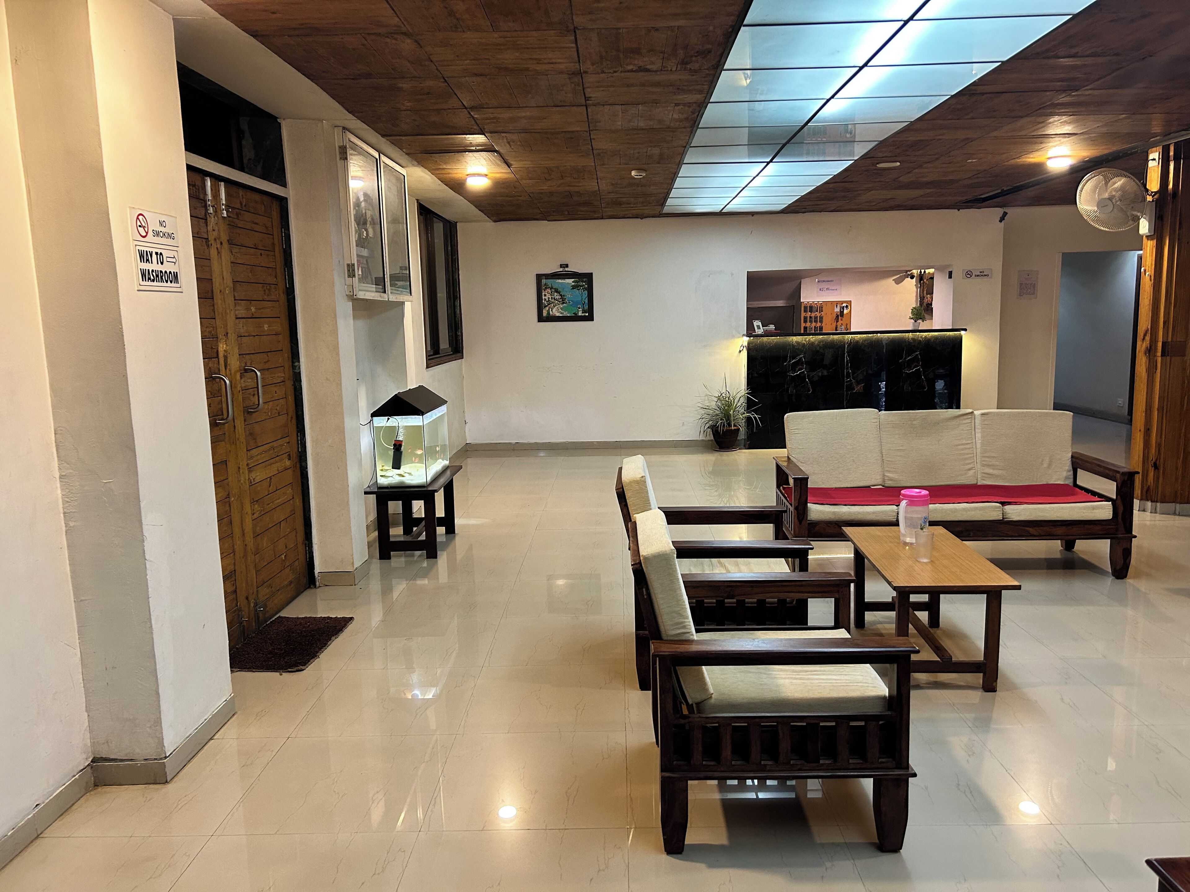 Una hall d'albergo con soffitto in legno, un acquario, un divano e un tavolino con un cuscino rosso.