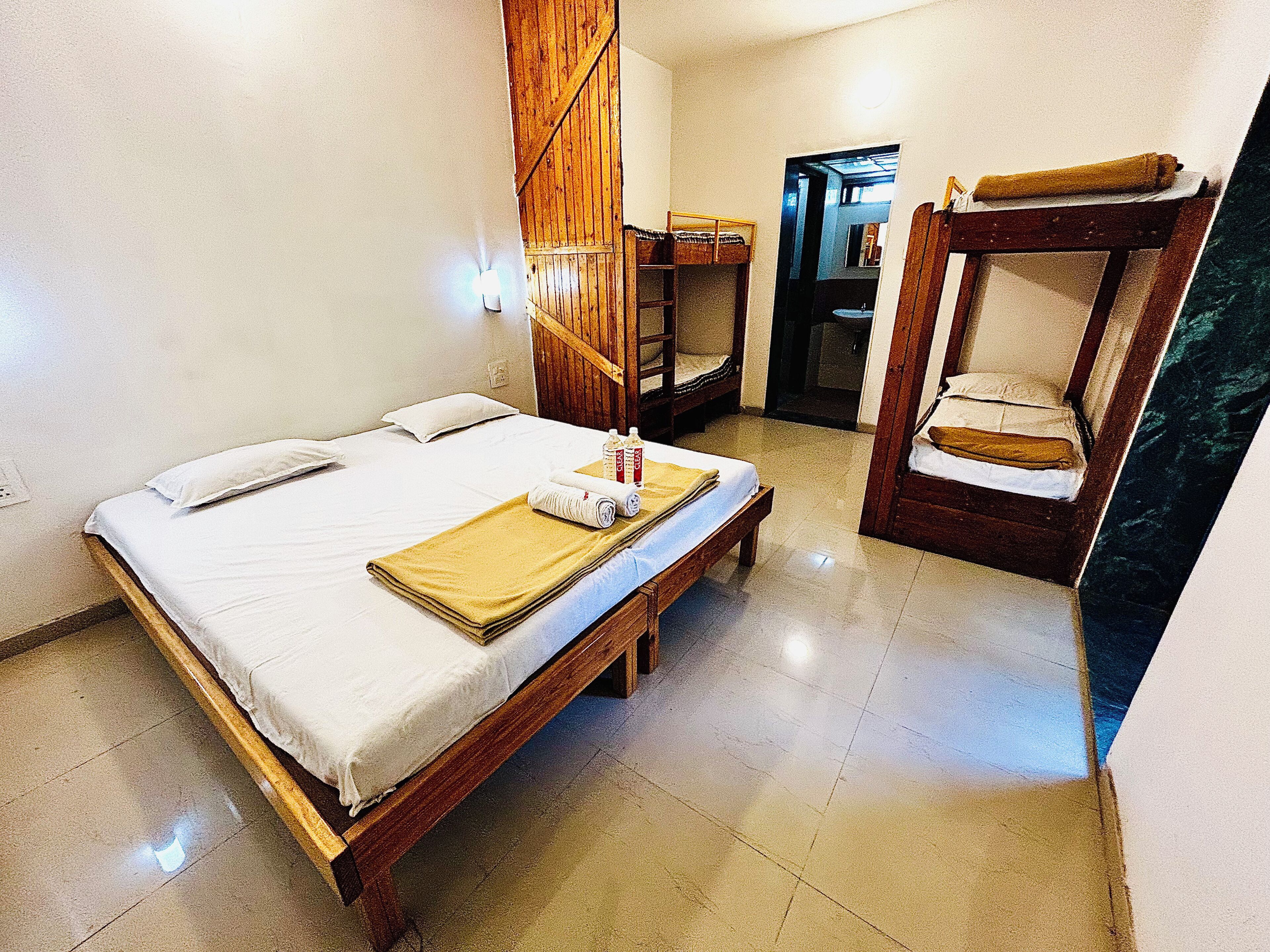A room with a bed, a wooden bench, a small table, and a mirror.