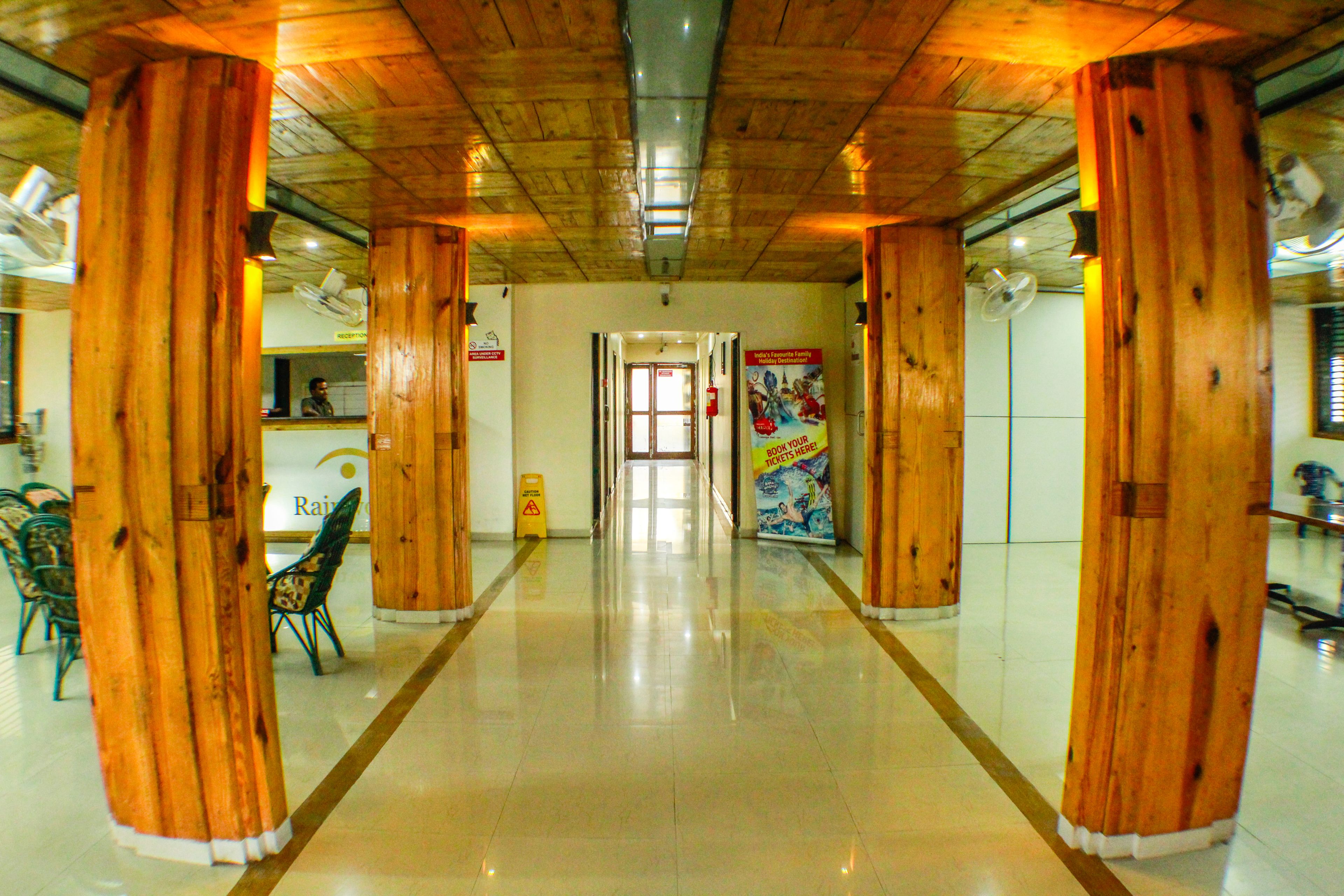 A hallway with wooden pillars, a reception desk, and a poster on the wall.