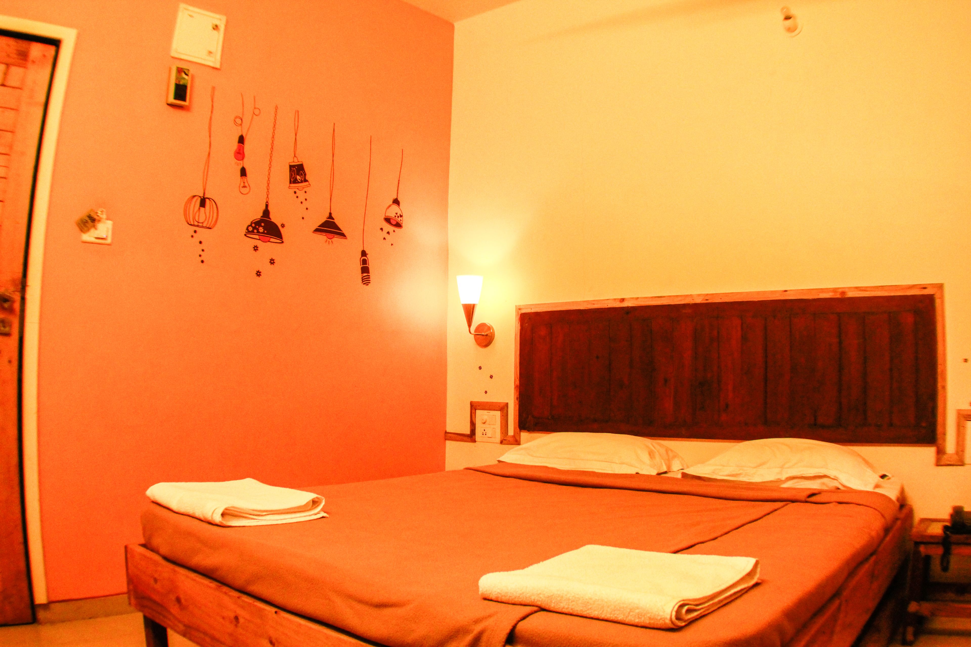 Quarto com cama, mesa de cabeceira e luminária na parede.