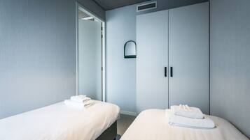 A hotel room with two beds, a wardrobe, and a mirror.