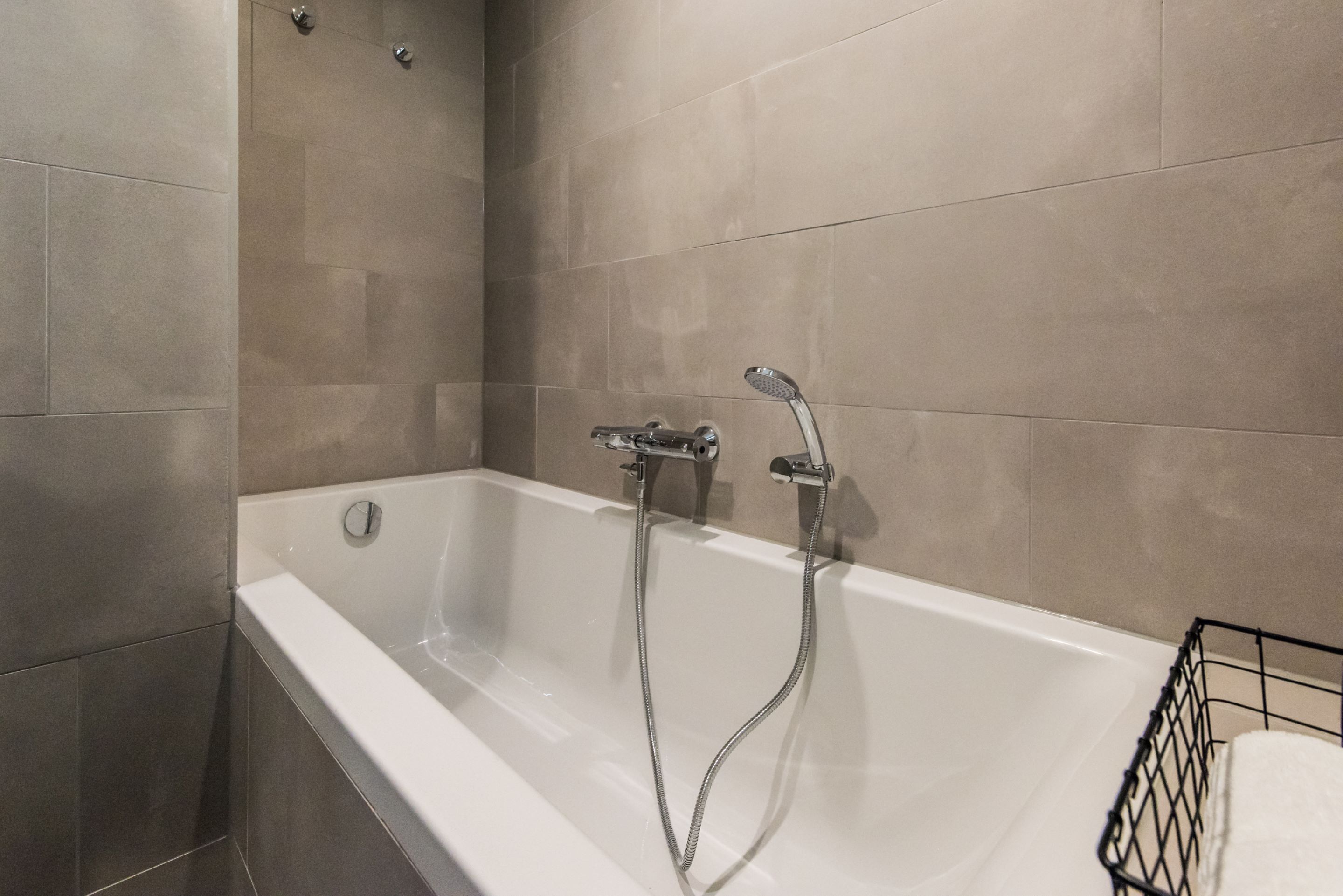 Une salle de bain moderne avec une baignoire blanche, deux pommes de douche et un porte-serviettes noir.